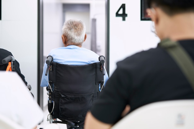 Pacientes mayores sentados en silla de ruedas mientras esperan que un médico los trate.