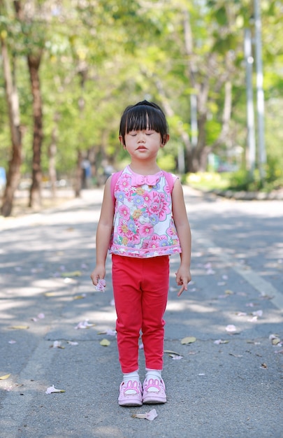 Pacífica da menina asiática pequena bonito da criança no parque público.