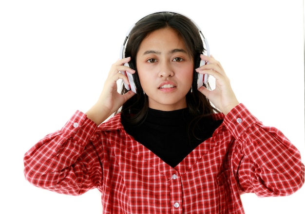 Pacífica mulher asiática com roupa legal, ouvindo música em fones de ouvido em fundo branco no estúdio.
