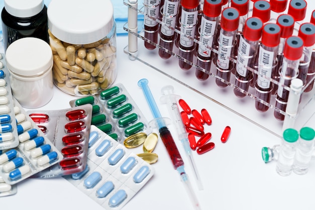 Packungen mit Pillen und Kapseln mit Medikamenten und Blutreagenzgläsern