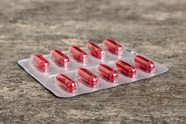 Pacote blister com vitamina a em fundo colorido Pílulas medicinais em um fundo claro Medicamentos e pílulas prescritas fundo plano comprimidos médicos vermelhos em blister