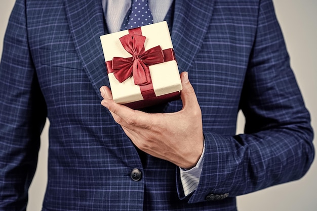 Pacote de caixa amarrado com fita vermelha elegante sendo realizada em estilo formal de mão masculina para presente de celebração de feriado