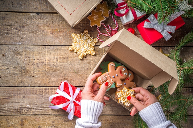 Pacote de caixa de presente de Natal. Conceito de troca de presentes de Natal de ano novo na pandemia covid-19. Secret Santa post game. Embalagem de presentes, biscoitos em pacote. Fundo de madeira, com galho de árvore de Natal e decoração