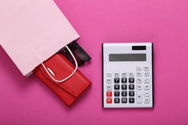 Pacote de compras com compras e calculadora em um fundo rosa Conceito de compras