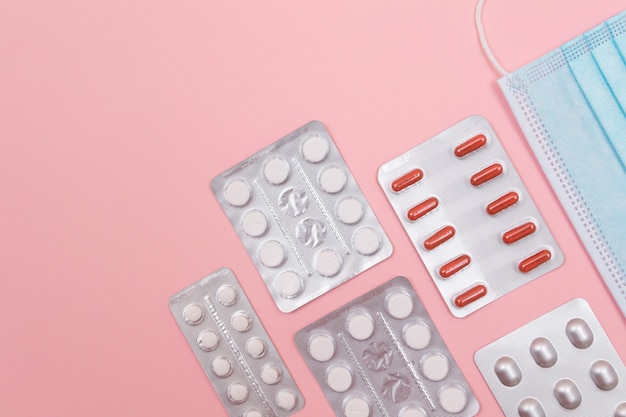 Pacote de comprimidos e comprimidos diferentes em fundo rosa