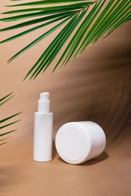 Pacote de garrafa de loção de creme de maquiagem de cosméticos de beleza para a pele em fundo de papel bege com folhas de palmeira tropicais e sua sombra