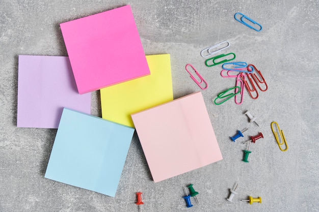 Pacotes de adesivos de papel para escrever notas e clipes de papel com botões de papelaria fundo de concreto cinza