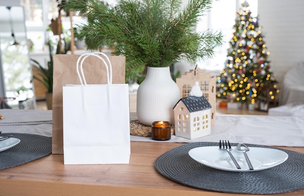 Pacotes de papel simulados estão na mesa da cozinha servida decorada para compras de Natal e presentes e refeições prontas são entregues e preparadas para o ano novo