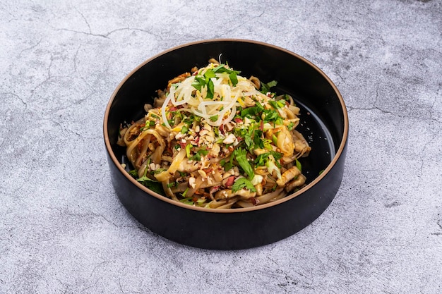 Foto pad thai mit huhn auf einem teller auf einem grauen hintergrund