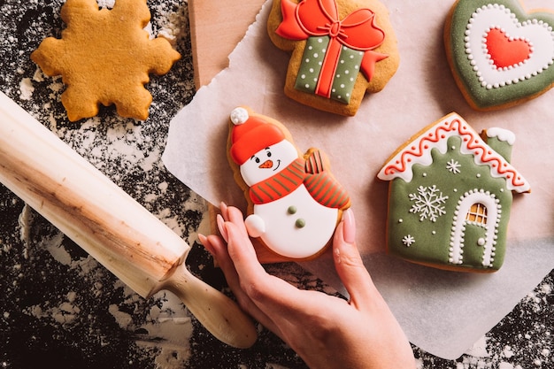 Padaria de Natal, pastelaria decorada festiva, biscoitos caseiros irreconhecíveis, segurando a mão feminina