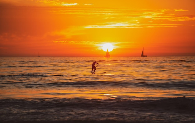 Paddle boarding Menschen auf dem Tretboot auf dem Meer bei Sonnenuntergang