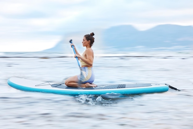 Paddle surf mar y fitness con una deportista flotando en el agua en la naturaleza para el bienestar o el ejercicio Entrenamiento en la tierra y viajar con una atleta en una paddleboard mientras está de vacaciones para viajar