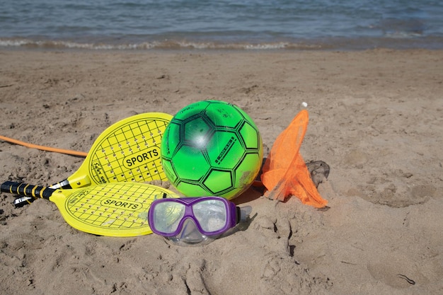 Paddle-Tennisschläger und Ball in gelber Farbe und Strandspielball am Strand. Kopierraum