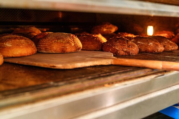 Foto padeiro anônimo mãos habilidosas deslizam massa fresca para o forno com uma pá