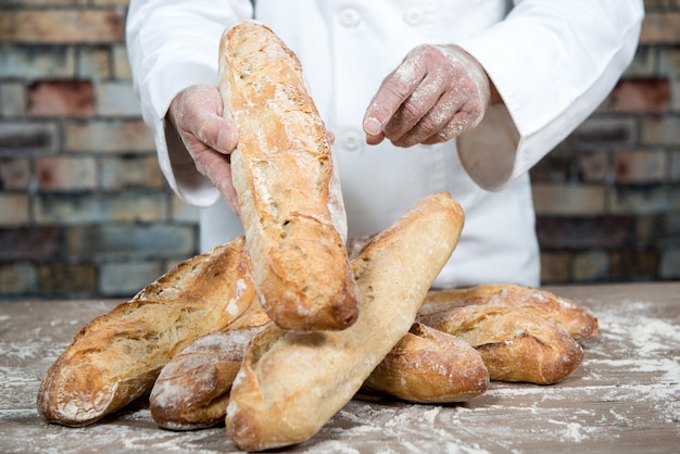 Padeiro com pão tradicional francês baguetes