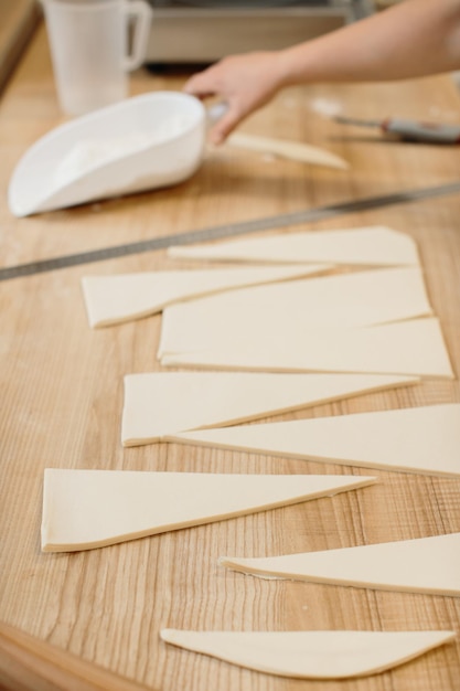 Padeiro de mulher corta a massa em triângulos para croissants Fazendo croissants na padaria