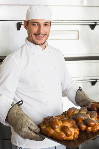 Padeiro feliz mostrando bandeja de pão fresco