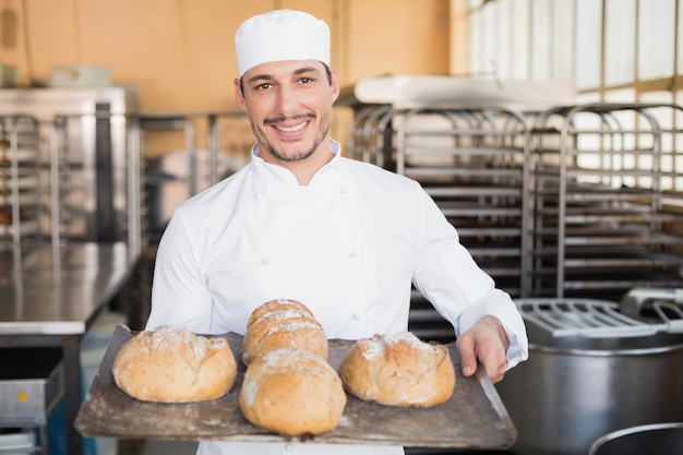 Padeiro feliz mostrando bandeja de pão fresco