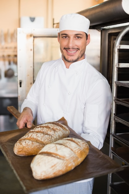 Padeiro feliz segurando bandeja de pão fresco