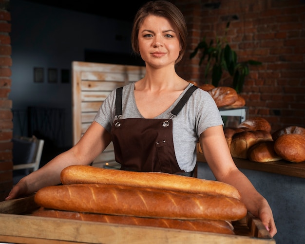 Foto padeiro feminino com pão assado na confeitaria