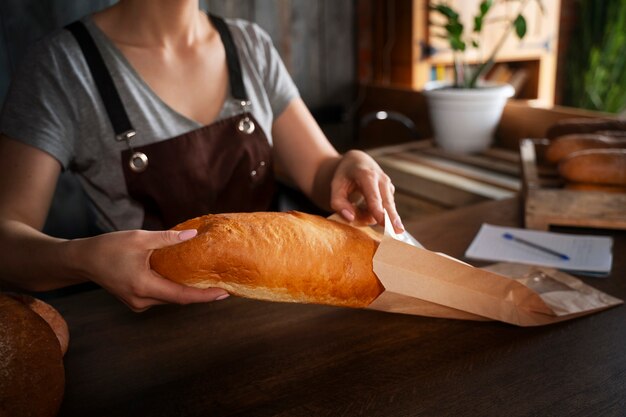 Foto padeiro feminino com pão assado na confeitaria