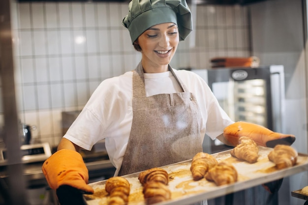 Padeiro feminino na cozinha segurando croissants recém-assados