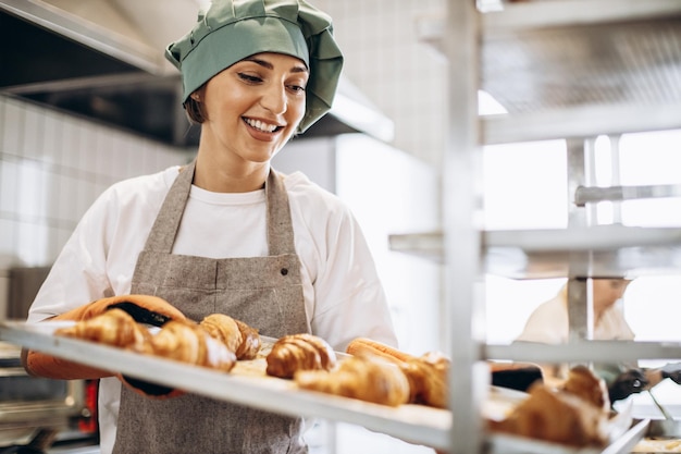 Padeiro feminino na cozinha segurando croissants recém-assados