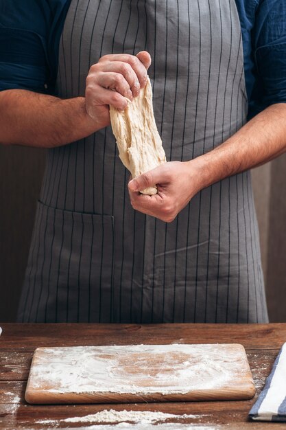 Padeiro irreconhecível esticando massa na cozinha