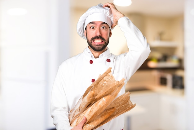 Padeiro jovem frustrado segurando um pouco de pão na cozinha
