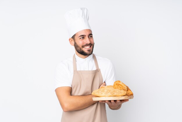 Padeiro masculino segurando uma mesa com vários pães na risada branca