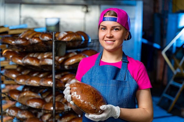 Padeiro profissional tem pão nas mãos. Produção industrial de pão. Olhando para a câmera. Fechar-se.