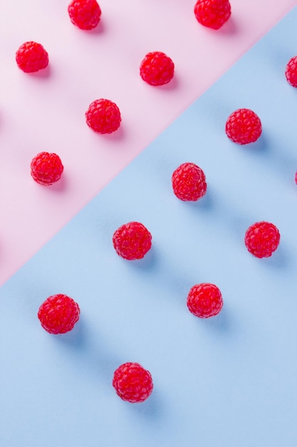 Foto padrão de framboesas em fundo rosa-azul dieta colorida e conceito de comida saudável