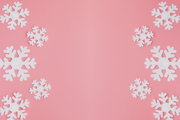 Padrão de inverno feito de flocos de neve e em fundo rosa.