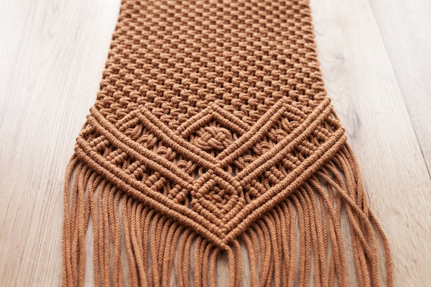 Padrão de macramé feito à mão close-up. Trança macramê e fios de algodão na mesa de madeira. Passatempo feminino. Eco amigável tricô moderno DIY conceito de decoração natural no interior. Copie o espaço