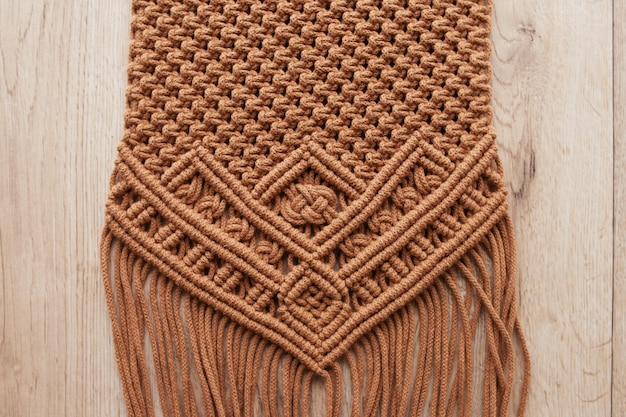 Padrão de macramé feito à mão close-up. Trança macramê e fios de algodão na mesa de madeira. Passatempo feminino. Eco amigável tricô moderno DIY conceito de decoração natural no interior. Copie o espaço