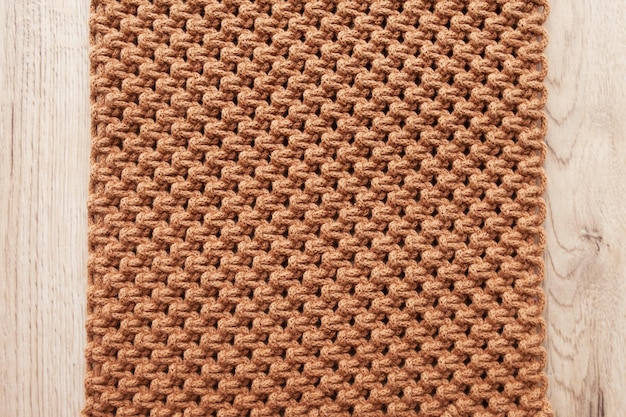 Foto padrão de macramé feito à mão close-up. trança macramê e fios de algodão na mesa de madeira. passatempo feminino. eco amigável tricô moderno diy conceito de decoração natural no interior. copie o espaço