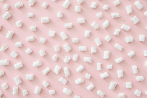 Foto padrão de marshmallow em fundo rosa pastel. flat lay, vista de cima, copie o espaço. con inverno