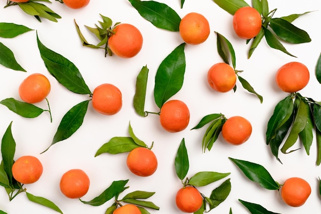 Padrão feito de tangerinas com folhas verdes em um fundo branco