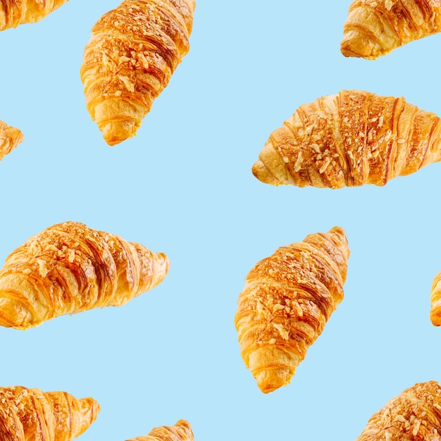 Padrão perfeito feito de croissant fresco com queijo isolado em fundo azul