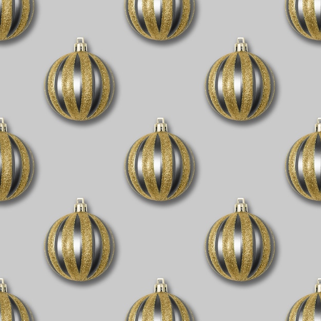 Padrão sem emenda com decorações de Natal de ouro e prata em um fundo cinza.