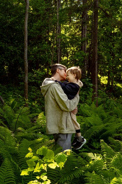 Foto padre abrazando a su hijo mientras está de pie en el bosque.