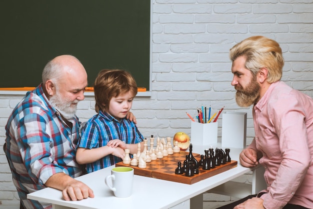 Padre abuelo enseñando al niño a jugar al ajedrez. Paternidad y paternidad.