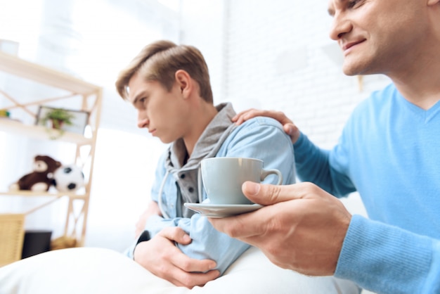 El padre se acerca con el café en la mano.