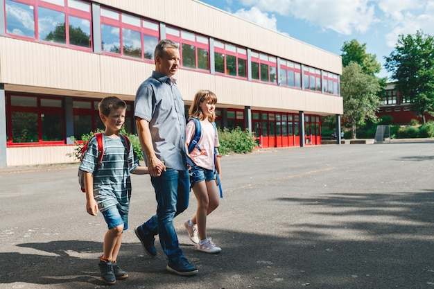 Foto el padre acompaña o recoge a los niños de la escuela al comienzo del año escolar