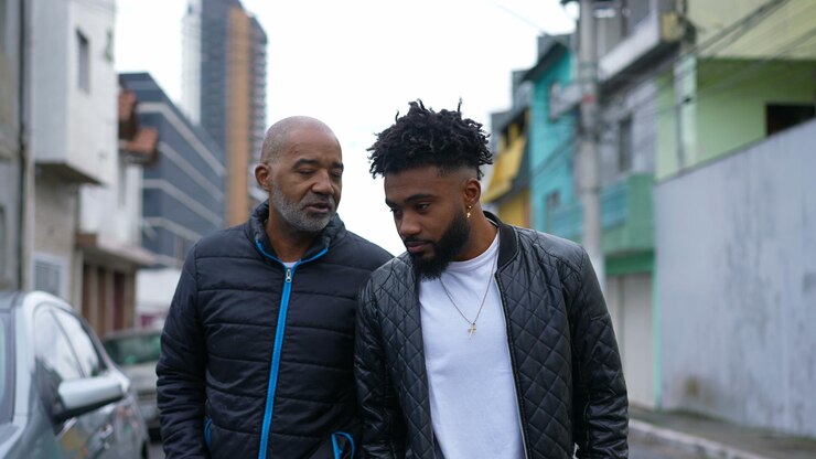 Foto un padre africano y un hijo adulto caminando juntos afuera en la calle urbana dos personas uniéndose
