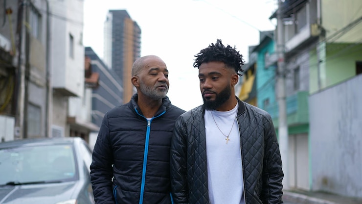 Foto un padre africano y un hijo adulto caminando juntos afuera en la calle urbana dos personas uniéndose