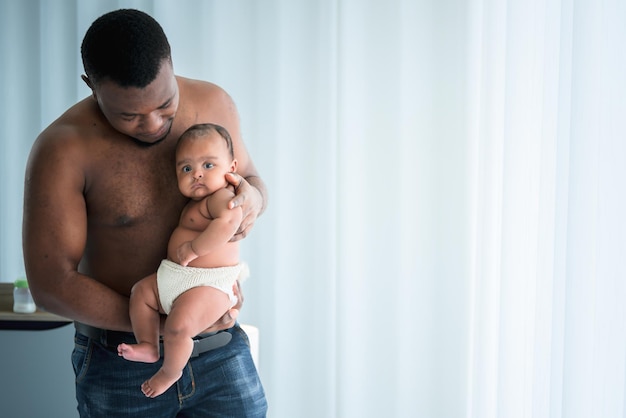 Padre africano sosteniendo a su hija recién nacida de 3 meses que es protección y feliz