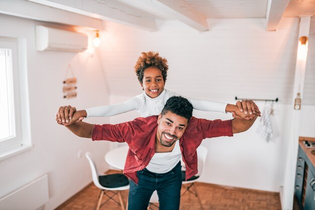 Padre afroamericano e hija que se divierten en casa.