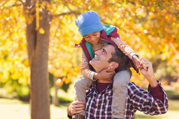 Padre alegre con hijo en el hombro en el parque