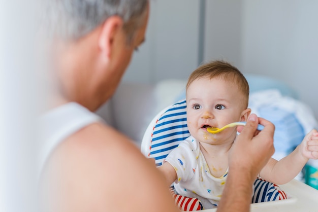 Padre alimentación bebé niño en silla alta